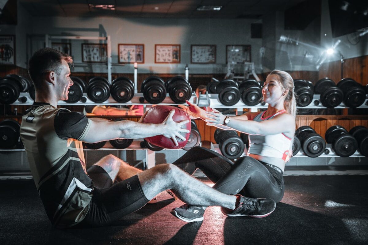 A couple engaged in a fitness session using a medicine ball in a gym environment.