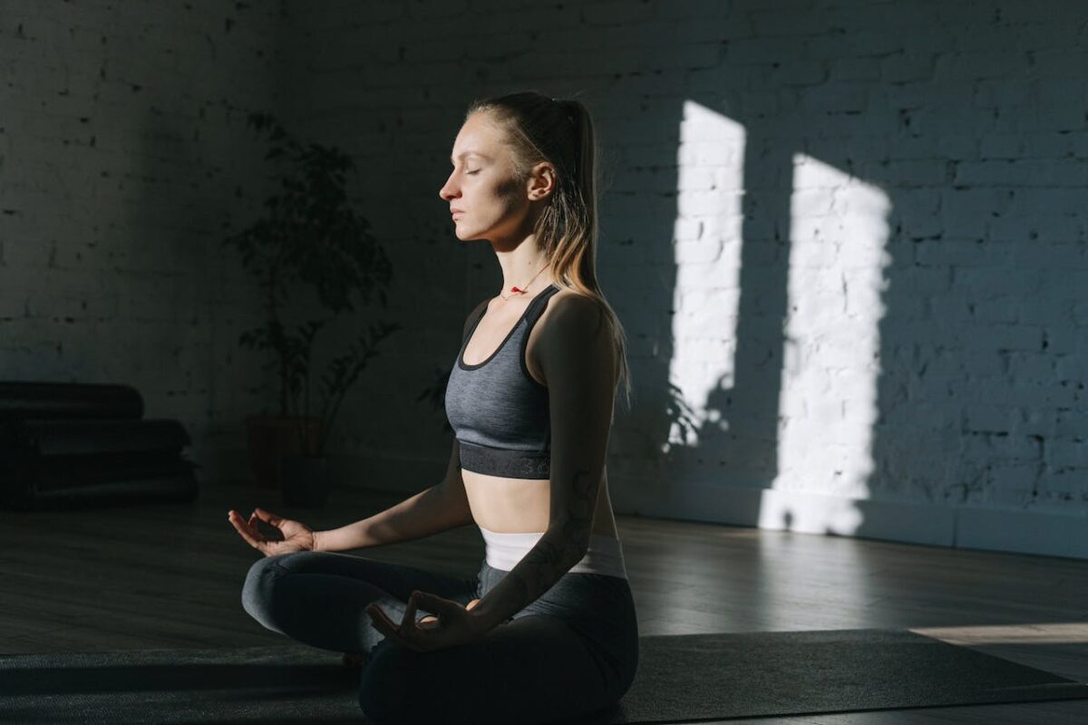 Woman in lotus position meditating indoors, embracing mindfulness and tranquility.