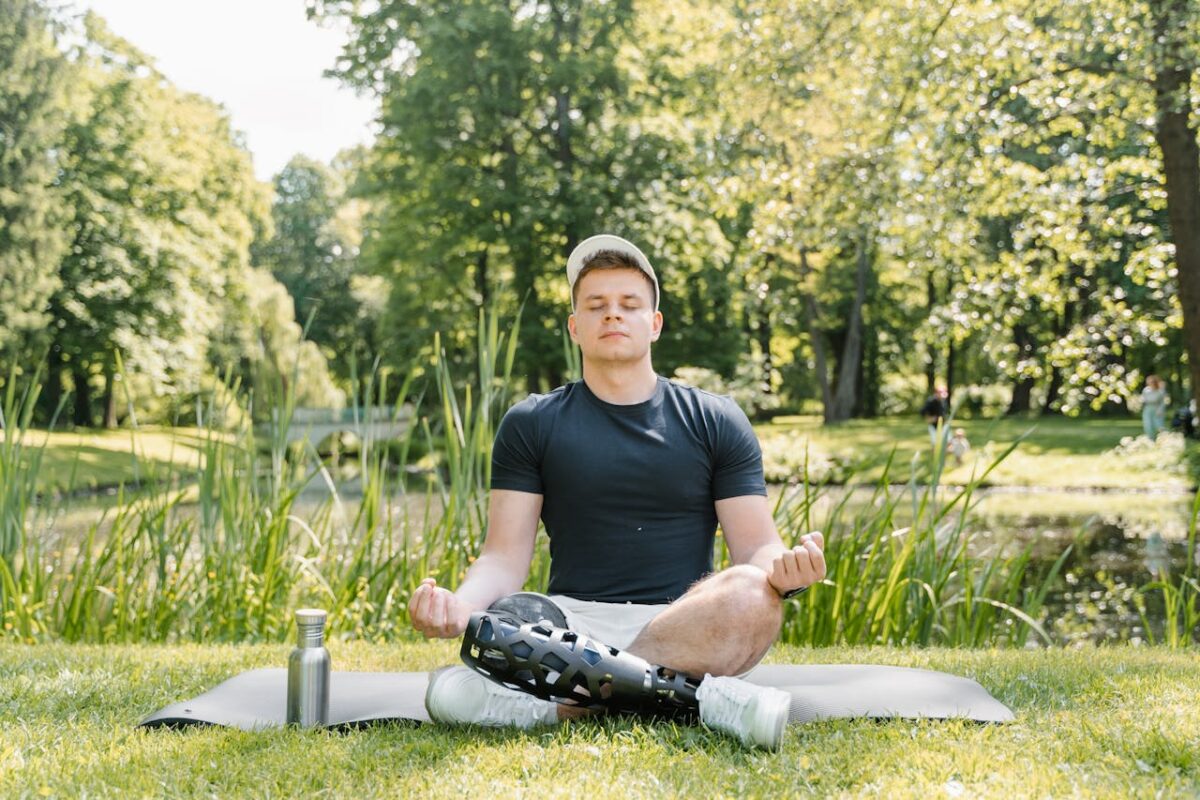 A man practicing meditation on a yoga mat outdoors, embracing wellness and relaxation.